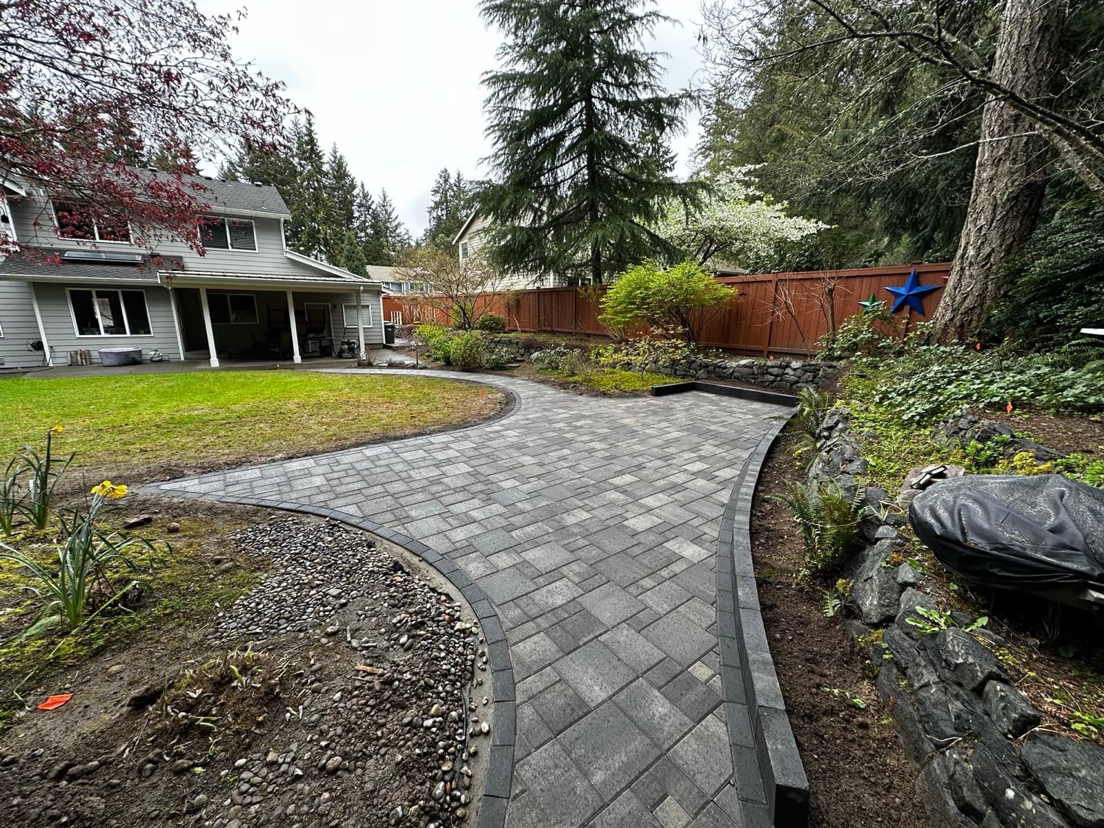 Completed backyard with pavers, turf, and retaining walls