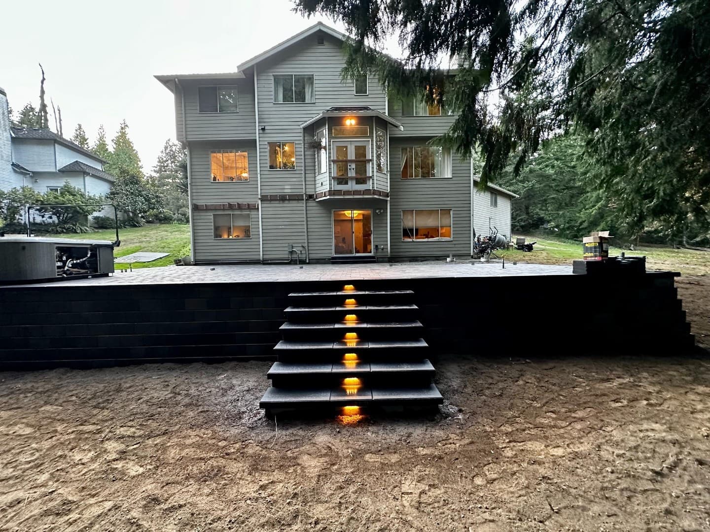 Raised dark paver patio with lit steps at dusk, Gig Harbor WA