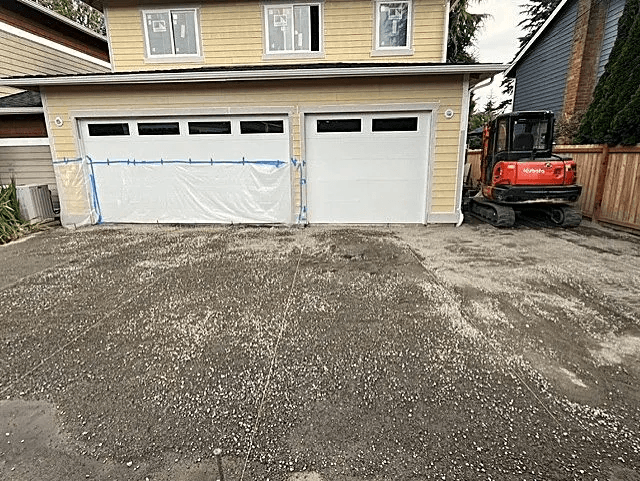 Existing 25-year-old driveway removed and prepared for replacement beside a garage